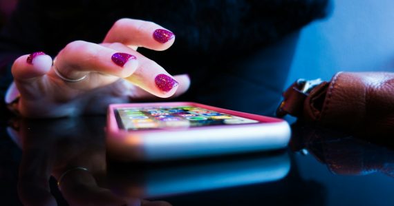 Person using black smartphone with gray and pink case, illustrating contraband smartphones in Indiana jails