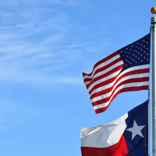 Two american and texas flags waving in the wind, illustrating a jail cell phone bribery case