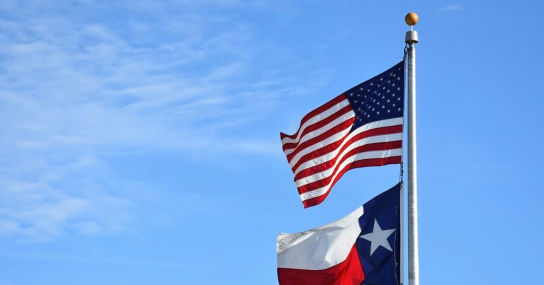Two american and texas flags waving in the wind, illustrating a jail cell phone bribery case