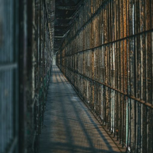 Dimly lit prison corridor with barred cells, illustrating in-cell phones versus contraband cellphones