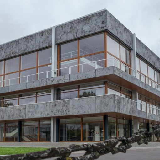 Modern concrete building with large windows and a chain fence, illustrating cell phones in federal prisons