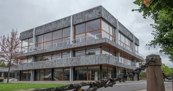 Modern concrete building with large windows and a chain fence, illustrating cell phones in federal prisons