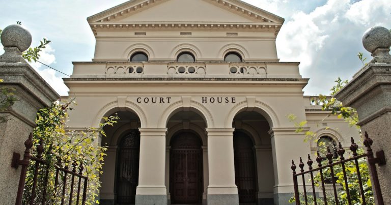 A large white building with a gate in front of it, illustrating the risk of leaving prison phones legal