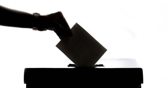A person is casting a vote into a box, illustrating California Senate passing a smuggling bill