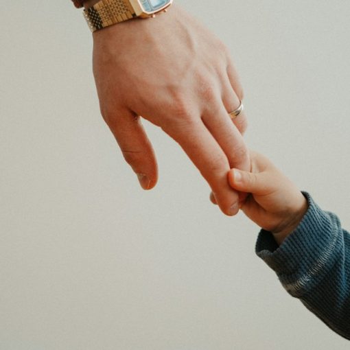 A person holding the hand of a child, illustrating the impact of incarceration on children
