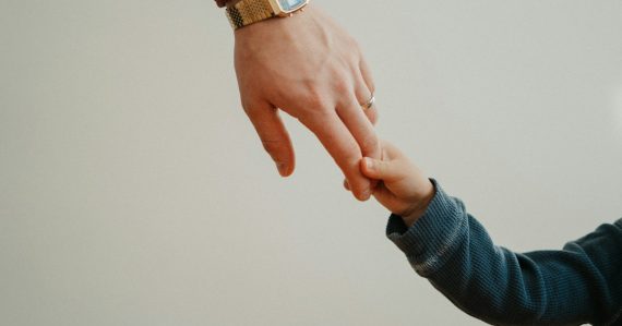 A person holding the hand of a child, illustrating the impact of incarceration on children