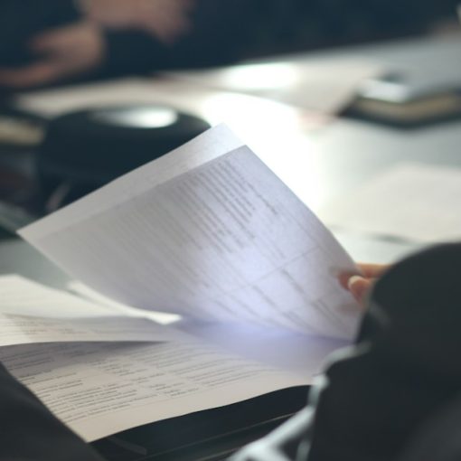 A woman sitting at a table reading a paper, illustrating California's contraband phone bill