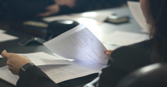A woman sitting at a table reading a paper, illustrating California's contraband phone bill
