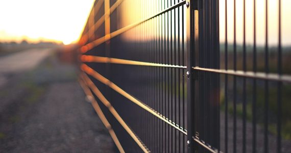 Black metal fence during sunset, illustrating contraband thrown over prison fences