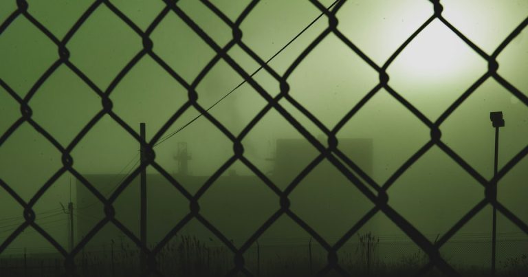 Black metal fence with chain link fence, illustrating supply and demand for contraband phones
