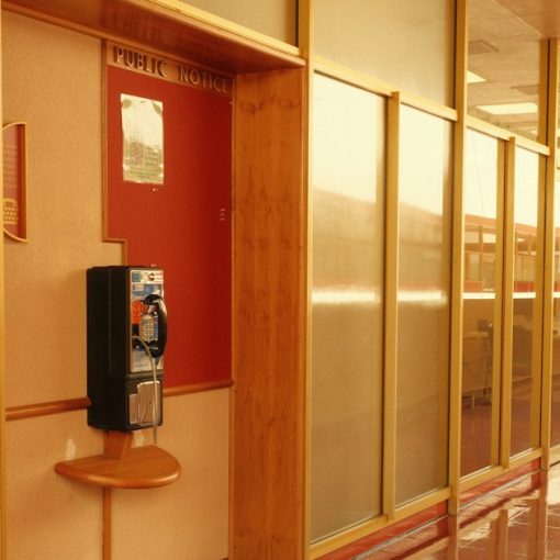Long hallway with a payphone and reflective walls, illustrating payphone problems in county jails