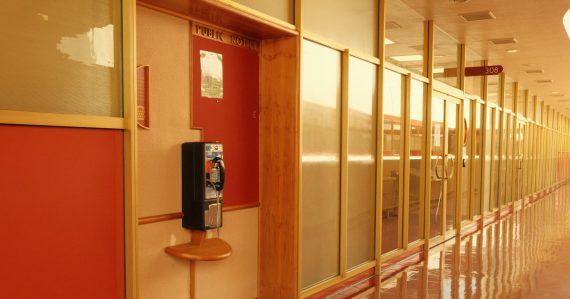 Long hallway with a payphone and reflective walls, illustrating payphone problems in county jails