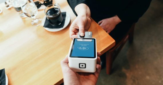 Person holding credit card swipe machine, illustrating an inmate running a credit card scam