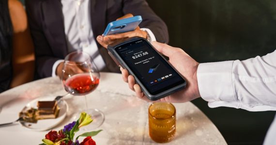 Man paying with phone at restaurant table, illustrating in-cell phones planned for a new jail