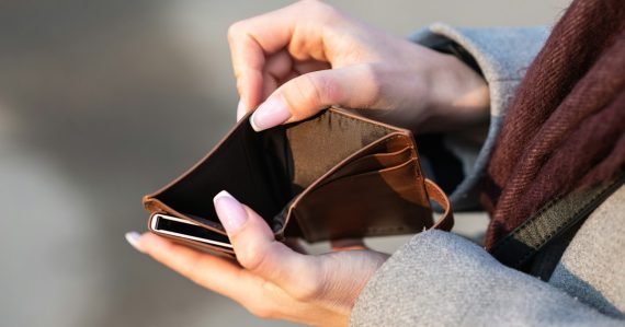 Hands holding empty wallet and phone, illustrating budget cuts in South Carolina prisons