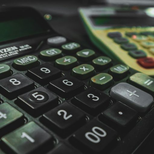 A calculator sitting on a table next to another calculator, illustrating the economics of prison payphone calls
