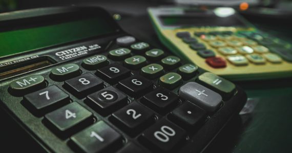 A calculator sitting on a table next to another calculator, illustrating the economics of prison payphone calls