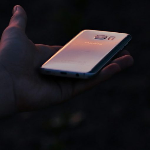 A person holding a cell phone in their hand, illustrating an ex-con arrested for smuggling phones
