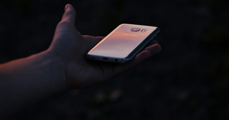 A person holding a cell phone in their hand, illustrating an ex-con arrested for smuggling phones