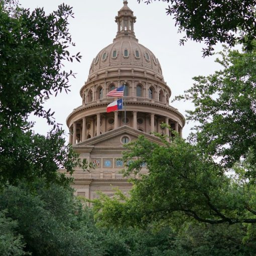 Texas state capitol building framed by trees, illustrating Texas prison phone smuggling consequences