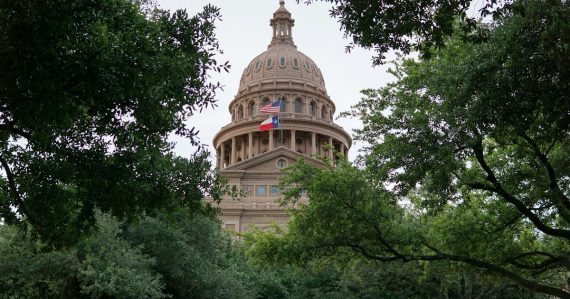 Texas state capitol building framed by trees, illustrating Texas prison phone smuggling consequences