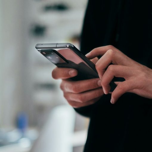 Person holding black android smartphone, illustrating DOJ cell phone rules for reentry