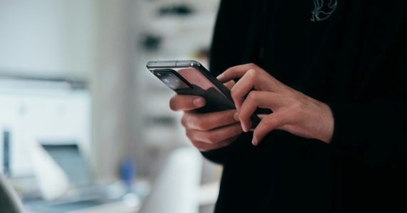Person holding black android smartphone, illustrating DOJ cell phone rules for reentry