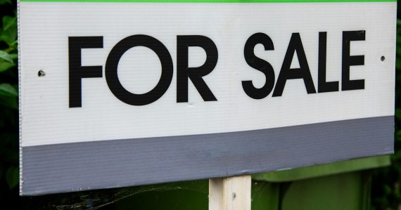A green and white for sale sign with a bird perched on it, illustrating Global Tel*Link being shopped for sale