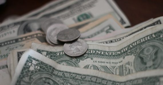 Photo of dollar coins and banknotes, illustrating the high cost of prison phone calls