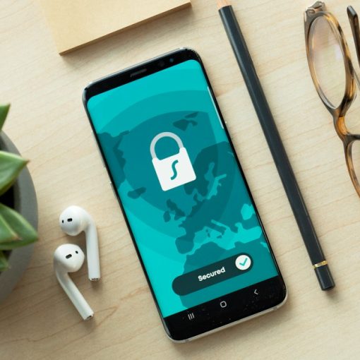A smartphone displaying a security lock icon on a wooden desk with a succulent, illustrating prison phone costs and privacy