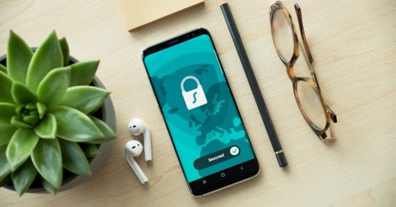 A smartphone displaying a security lock icon on a wooden desk with a succulent, illustrating prison phone costs and privacy