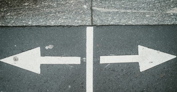Two white arrows pointing in opposite directions on asphalt, illustrating competition in the prison payphone industry