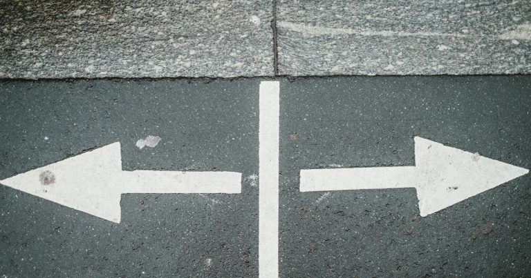 Two white arrows pointing in opposite directions on asphalt, illustrating competition in the prison payphone industry