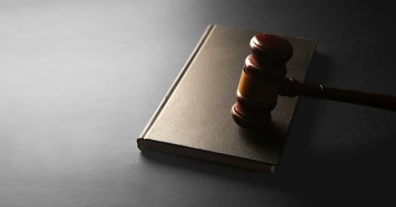 A wooden gavel rests on a closed book, illustrating an inmate pleading guilty to smuggling