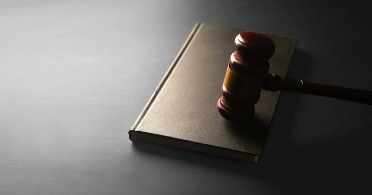 A wooden gavel rests on a closed book, illustrating an inmate pleading guilty to smuggling