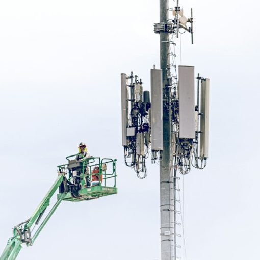 A man on a lift working on a cell phone tower, illustrating the fight over jamming prison cell phones