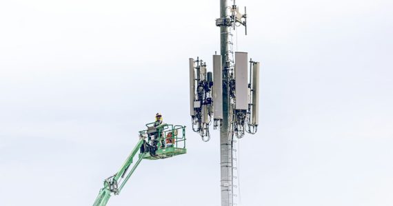 A man on a lift working on a cell phone tower, illustrating the fight over jamming prison cell phones