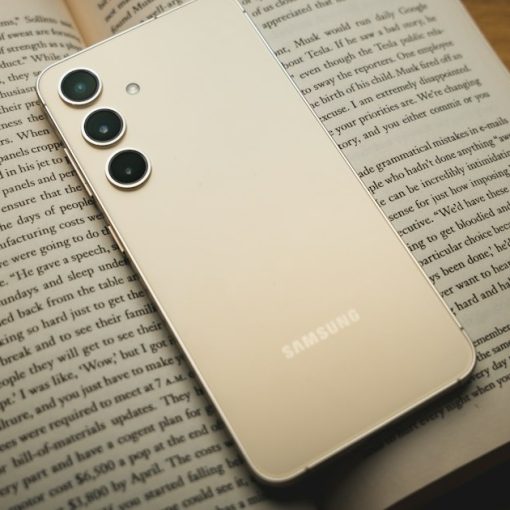A white samsung phone sitting on top of an open book, illustrating the high value of contraband phones