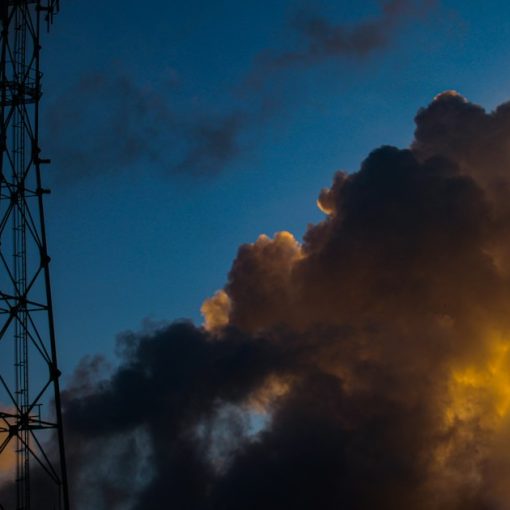 Cell tower silhouetted against a dramatic sunset sky, illustrating caution on prison managed access