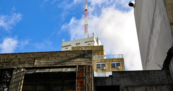 Tall radio tower atop a building under blue sky, illustrating managed access deployments in US prisons