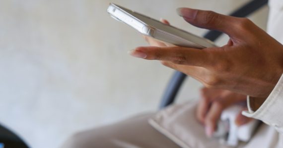 A close up of a person holding a cell phone, illustrating prisoners outwitting phone blocking