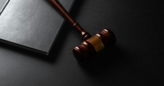 Wooden gavel resting on a dark surface next to book, illustrating a NJ officer convicted of smuggling