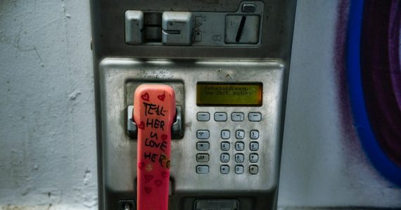 An old pay phone with graffiti on it, illustrating Michigan using phone revenue for jammers