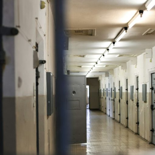 A long prison corridor with rows of metal doors, illustrating a prison chief recommending in-cell phones
