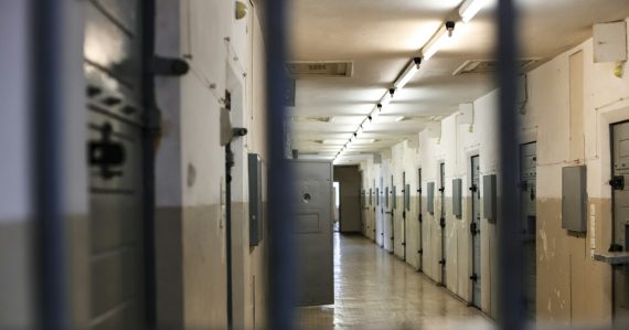 A long prison corridor with rows of metal doors, illustrating a prison chief recommending in-cell phones