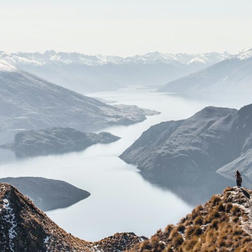 People on a rocky mountain peak overlooking a large lake and snowy mountains, illustrating in-cell phones at a new NZ prison