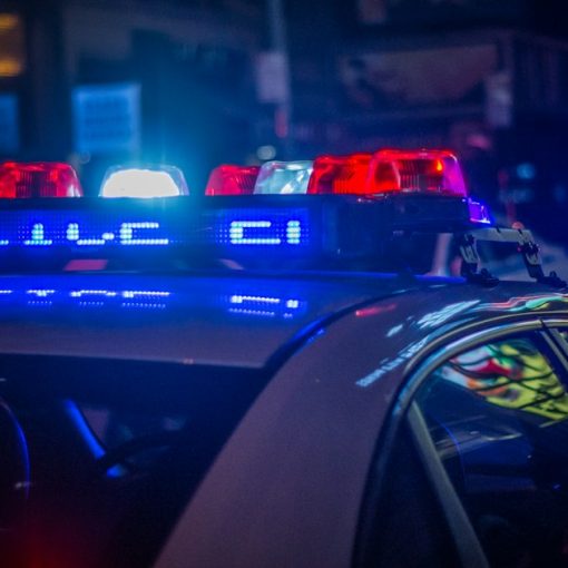 A police car with flashing red and blue lights on a city street, illustrating a raid at Costa Rica's La Reforma prison
