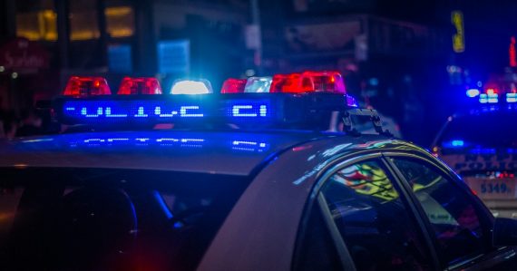 A police car with flashing red and blue lights on a city street, illustrating a raid at Costa Rica's La Reforma prison