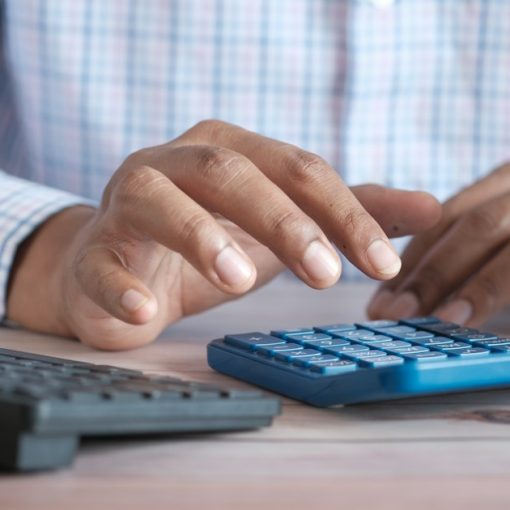 Person using calculator at desk with coffee mug, illustrating state prison budget pressures