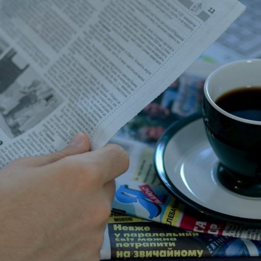 A person reading a newspaper with a cup of coffee, illustrating a roundup of contraband phone news